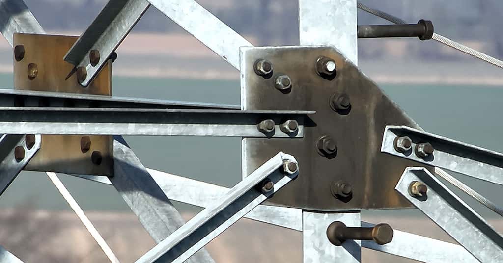 Drohne inspiziert Freileitungsmast, Fokus auf Blech und Verschraubungen, durchgeführt von Multikopterdienst